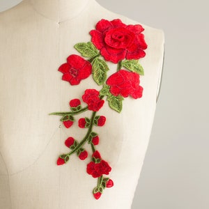 May include: Red embroidered floral applique with a large rose and smaller flowers and leaves.