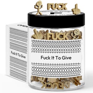 May include: A clear glass jar with a black lid, filled with wooden cutouts of the word "FUCK", middle fingers, and stick figures. The jar has a label that reads "Fuck It To Give". A white box with the text "Fuck It To Give" is on the left.
