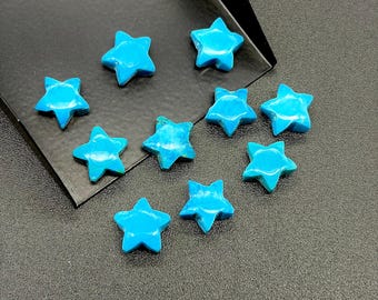 May include: Ten turquoise star-shaped gemstones are displayed on a dark grey surface. The stars are a bright blue colour, with subtle variations in texture. A black tray is visible in the upper right corner. Each star is approximately 1.5 cm across.