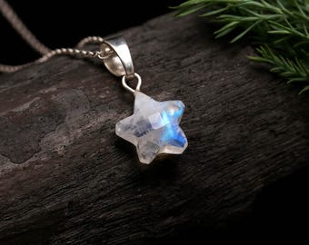 May include: A star-shaped moonstone pendant featuring a translucent, milky white appearance with a distinct blue adularescence. The gemstone is set in a polished silver-toned metal bail and hangs from a delicate silver-toned chain link necklace.