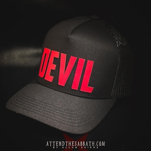 Puede incluir: Gorra de camionero negra con la palabra "DEVIL" en letras rojas en negrita en la parte delantera. La gorra tiene una parte trasera de malla y una visera curva. El texto "ATTENDTHESABBATH.COM" está impreso en blanco en la parte inferior.