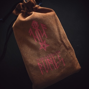 Pu&ograve; includere: Una pochette in velluto marrone con un ricamo rosso. Il ricamo presenta una stella e il testo "The Enchanted  Funey".