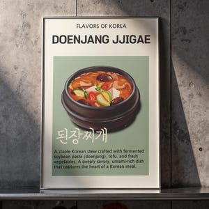 May include: A framed poster titled "Flavors of Korea" featuring "Doenjang Jjigae." The image shows a bowl of Korean stew with tofu, vegetables, and mushrooms. Text below describes the dish as a savory, umami-rich Korean meal.