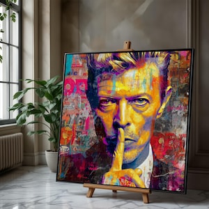 May include: A vibrant pop art portrait of a person with a finger over their lips, set against a collage background. The artwork features bold colors like yellow, purple, and red, and is displayed on a wooden easel.