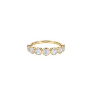 May include: A gold ring with seven round moonstone gemstones. The gemstones are set in a row, creating a continuous band of color. The ring has a simple, elegant design.