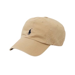 May include: A beige baseball cap with a curved peak. The cap has a small, dark blue embroidered logo of a polo player on the front. The hat is made of a soft, durable fabric and has a classic, adjustable design.