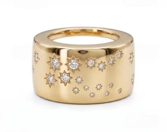 May include: A wide gold band ring featuring a polished finish and a celestial pattern of multiple star-shaped engravings. Several of these star motifs are set with small, clear, round-cut gemstones that sparkle against the smooth gold surface.