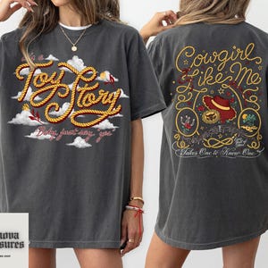 a woman wearing a gray t-shirt with a graphic design on the front and back.