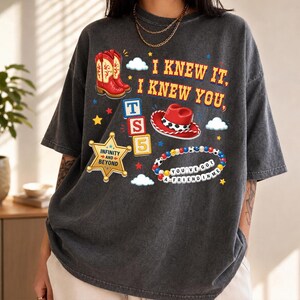 A person wearing a gray t-shirt with various cartoon-style icons and text printed on it.