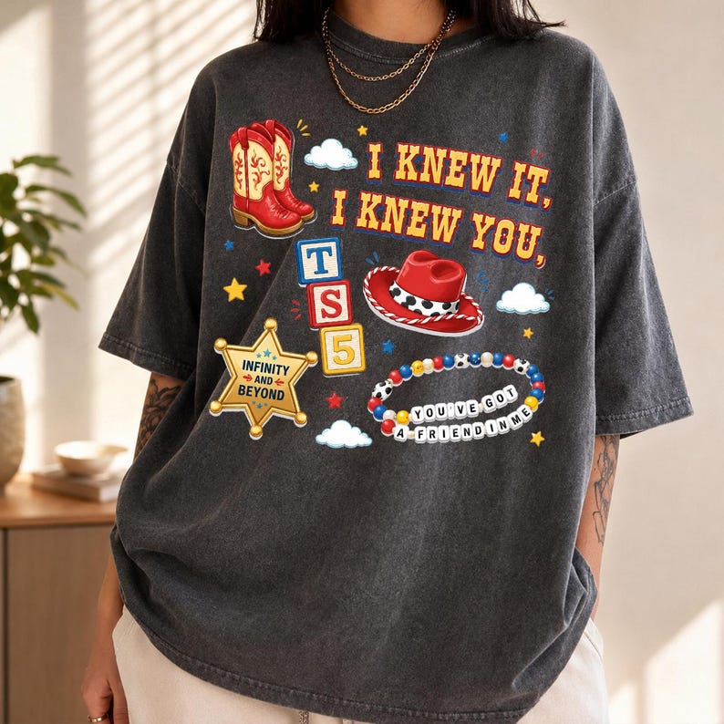 A person wearing a gray t-shirt with various cartoon-style icons and text printed on it.