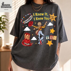 A person wearing a gray t-shirt with a graphic design featuring a cowboy hat, a star, and various other elements.