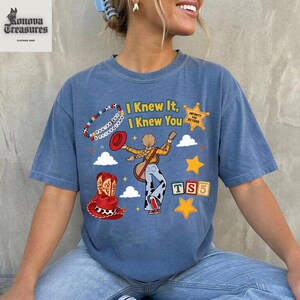 A woman wearing a blue t-shirt with a graphic design featuring a cartoon character and text.