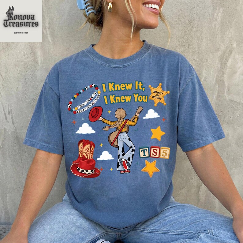 A woman wearing a blue t-shirt with a graphic design featuring a cartoon character and text.