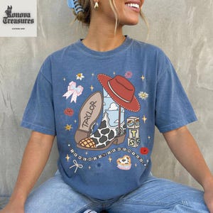 A woman wearing a blue t-shirt with a cartoon character and various other icons printed on it.