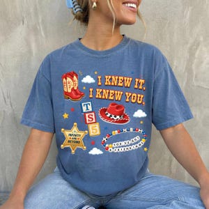 A woman wearing a blue t-shirt with various cartoon-style icons and text printed on it.