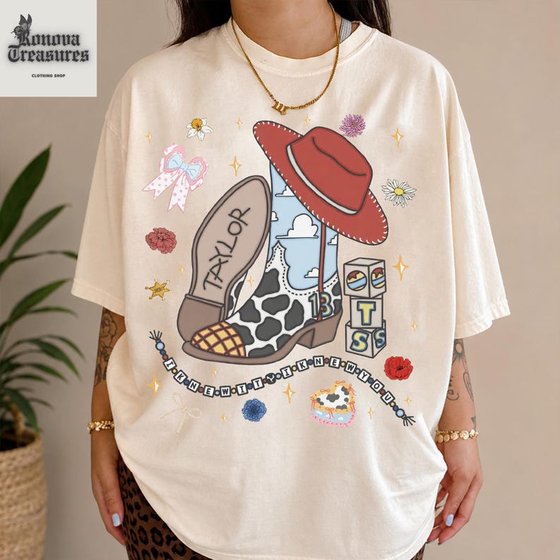 A person wearing a white t-shirt with a colorful graphic design featuring a cowboy hat, boots, and various other cartoon-style elements.