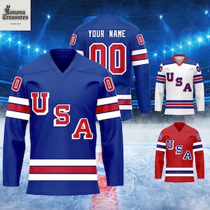 a collection of three different hockey jerseys, each with the word "USA" prominently displayed on the front. The jerseys are set against a backdrop of a hockey rink and a stadium, suggesting they are part of a sports apparel collection.