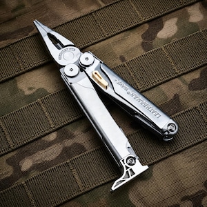 Pode incluir: Uma ferramenta multifunções Leatherman Wave+ em aço inoxidável prateado com alicates de pontas finas, corta-arames e um cabo gravado com o nome da marca e o modelo. A ferramenta inclui um pequeno mecanismo de bloqueio dourado e parafusos em estrela.