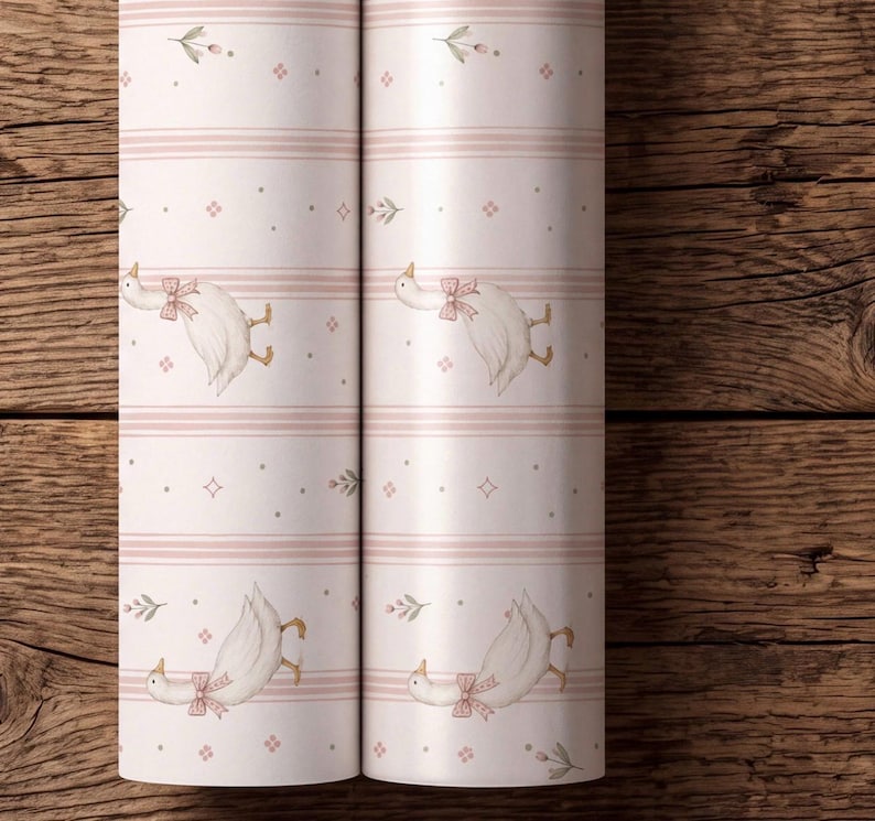 May include: Two rolls of light pink wallpaper featuring a repeating pattern of white geese wearing pink bows, interspersed with small floral sprigs, tiny four-pointed stars, and horizontal stripes in varying shades of soft pink and white.