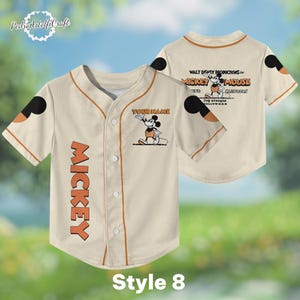 A beige baseball jersey with Mickey Mouse printed on it, featuring a personalized name tag and a Mickey Mouse logo.