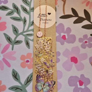 Set of four custom-initial gold-tone metal bookmarks with butterfly and floral filigree, personalized, in blue packaging.