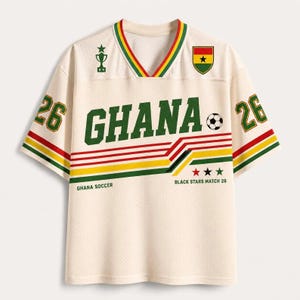 May include: An off-white V-neck jersey with green, yellow, and red accents. The front features the text GHANA, a soccer ball, a trophy icon, and the Ghana flag. The sleeves display the number 26, and the text GHANA SOCCER and BLACK STARS MATCH 26.