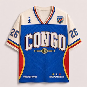 May include: A short-sleeve V-neck jersey in cream, blue, and red. The front features the text CONGO, a trophy icon, and a crest with CONGO DR. The sleeves display the number 26. Additional text includes CONGO DR SOCCER and KINSHASA MATCH 26.