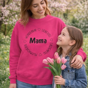 May include: A magenta sweatshirt with the word "Mama" in black, surrounded by German words and hearts. A young girl holds a bouquet of pink tulips and wears a denim jacket. The background is a soft focus of a flowering tree.