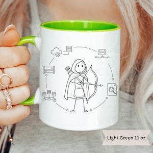 May include: White ceramic mug with a light green interior and handle. The mug features a black and white illustration of an archer surrounded by tech-related icons. Text at the bottom reads "Light Green 11 oz."