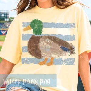 Pu&ograve; includere: T-shirt giallo chiaro con un disegno di anatra. L'anatra ha la testa verde, il corpo marrone e le zampe arancioni. Strisce orizzontali azzurre sono dietro l'anatra. Il testo "Wilder Pixels Png" &egrave; in basso.