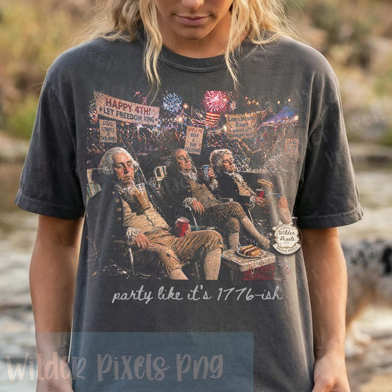 May include: Dark gray t-shirt featuring a graphic of historical figures enjoying drinks, fireworks, and the text "HAPPY 4TH! LET FREEDOM RING." The phrase "party like it's 1776-ish" is printed below the graphic.