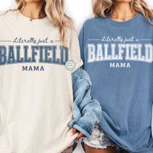 May include: Two long-sleeved t-shirts, one cream-colored and one blue, with the text "Literally just a BALLFIELD MAMA" in a vintage-style font. The shirts have a relaxed fit and are suitable for casual wear.