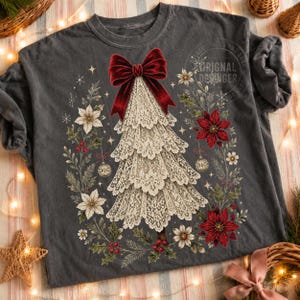 Pu&ograve; includere: Una t-shirt grigio antracite con la grafica di un albero di Natale realizzato in pizzo color crema, sormontato da un grande fiocco in velluto rosso. L'albero &egrave; circondato da una ghirlanda di stelle di Natale rosse e bianche e agrifoglio.