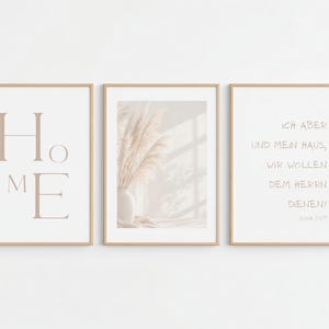 Könnte beinhalten: Drei gerahmte Wandbilder in hellen Holzrahmen. Das linke Bild zeigt das Wort HOME in großen beigen Buchstaben. Das mittlere Bild zeigt eine beige Vase mit Pampasgras. Das rechte Bild enthält den deutschen Text ICH ABER UND MEIN HAUS, WIR WOLLEN DEM HERRN DIENEN! JOSUA 24:15.