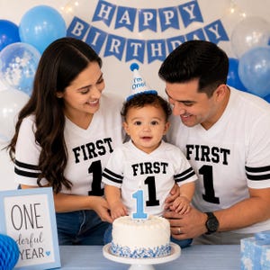 Pu&ograve; includere: Magliette bianche abbinate con scollo a V, strisce nere sulle maniche e la scritta FIRST 1 stampata in nero. Un piccolo cappellino da festa blu e bianco con la scritta I'm One! sulla testa di un bambino. Una torta bianca con una candela blu a forma di 1.