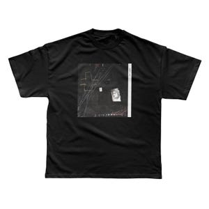 May include: Black t-shirt featuring a graphic design on the front. The design includes abstract shapes, lines, and a portrait. The text "XAVIER ME" is printed vertically on the right side of the graphic.