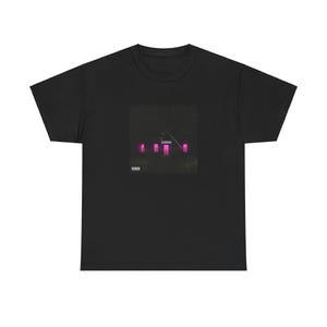May include: Black t-shirt featuring a square graphic with a dark background and neon pink rectangular shapes. The graphic also includes a triangular shape and a small text box in the lower left corner. The shirt is made of a soft material.
