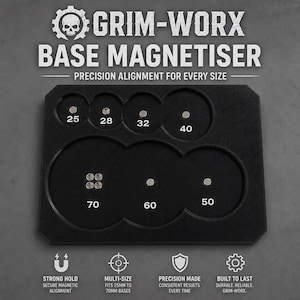 May include: A black Grim-Worx Base Magnetiser tool featuring circular cutouts labeled 25, 28, 32, 40, 50, 60, and 70 for precision alignment. The tool includes small circular magnets and text detailing strong hold, multi-size fit, and durable construction.