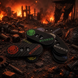 May include: A collection of black oval-shaped wound trackers with a carbon fiber texture. Each tracker features a gear-shaped skull icon in various colors, two numerical dials, and the word WOUNDS printed in a matching color on the right side.