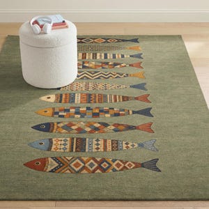 a rug with a fish design, placed on a wooden floor. There is a white ottoman or stool in the background, and a pair of headphones is resting on top of it.