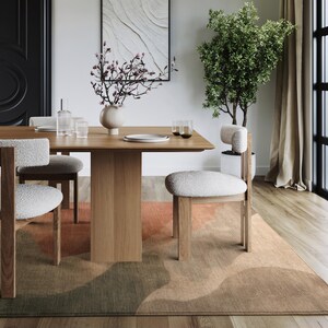 a modern dining room with a wooden table, white upholstered chairs, and a large window with a plant. The room has a minimalist and contemporary design, with a neutral color palette and clean lines.