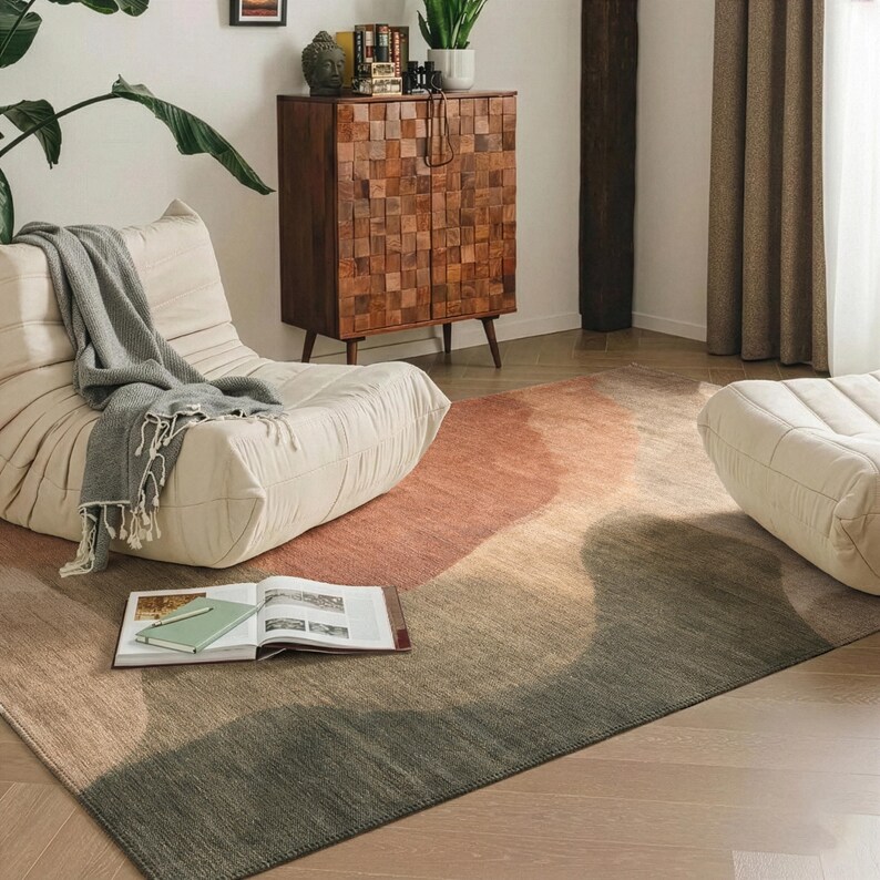 a cozy living room with a plush white sofa, a wooden cabinet, and a colorful rug. There are also some books and a plant in the room, creating a comfortable and inviting atmosphere.