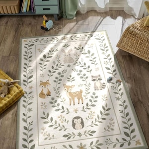 a rug with a forest-themed design, including various animals such as deer, foxes, and hedgehogs, surrounded by leaves and flowers. The rug is placed on a wooden floor, and there are some books and a toy car nearby.
