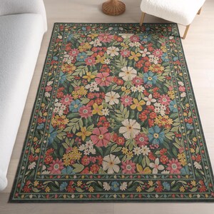 Peut inclure: Un tapis rectangulaire au fond gris anthracite orné d'un motif floral dense et coloré. Le design présente des fleurs roses, blanches, jaunes, rouges et bleues avec des feuilles vertes, entouré d'une bordure décorative de petites fleurs.