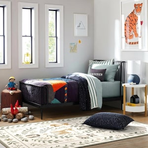 A child's bedroom with a bed, nightstand, and various toys and decorations. The room has a colorful and playful design, with a tiger-themed artwork on the wall and a patterned rug on the floor.