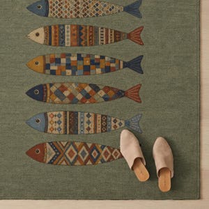 a rug with a fish design, and there are beige shoes placed on the rug.