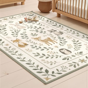 a rug with a forest scene design, including animals such as deer, hedgehog, and rabbit, along with leaves and flowers. The rug is placed on a wooden floor, and there is a crib visible in the background.