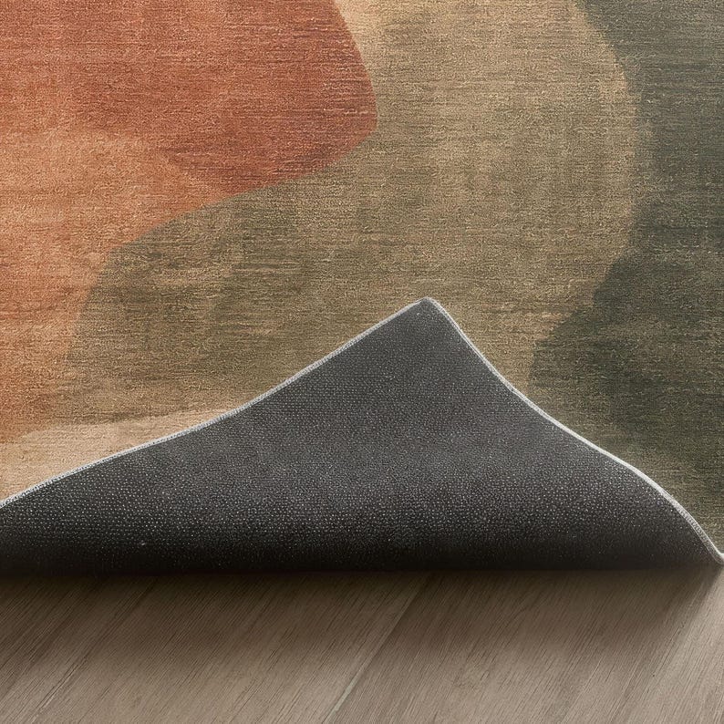 a close-up view of a rug with a geometric pattern in shades of brown and green, placed on a wooden floor.