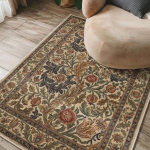 Pode incluir: Um tapete retangular com fundo creme apresentando um padrão denso e complexo de folhas de acanto, flores desabrochadas em tons de vermelho e laranja, e motivos de romãs, emoldurado por uma borda floral decorativa.