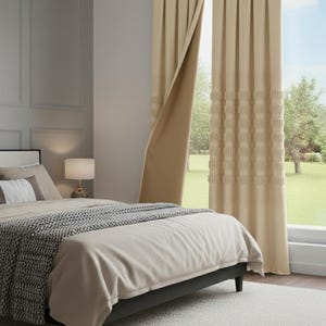 Könnte beinhalten: Ein Schlafzimmer mit einem Bett mit beiger Bettdecke und gemusterter Decke. Beige Vorhänge rahmen ein Fenster mit Blick auf einen grünen Rasen ein. Ein flauschiger weißer Teppich bedeckt den Boden und schafft eine gemütliche Atmosphäre.